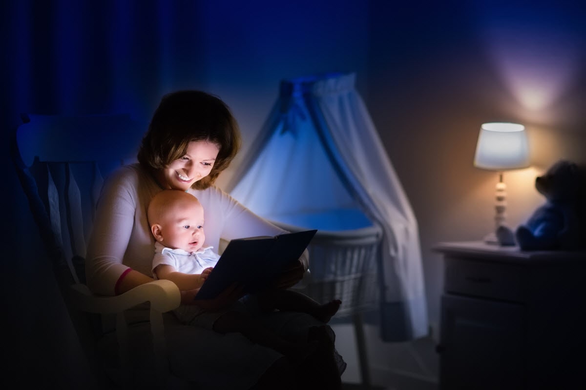 A mom sitting on a chair teaching her baby to read