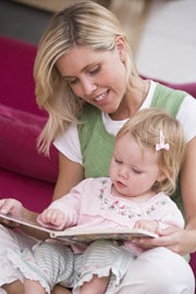 a mother reading with her two year old daughter and showing her all about storybooks