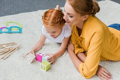 Mom and daughter playing word games with letter blocks