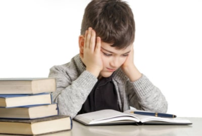 A young boy struggling to read a book that is too advanced for his age