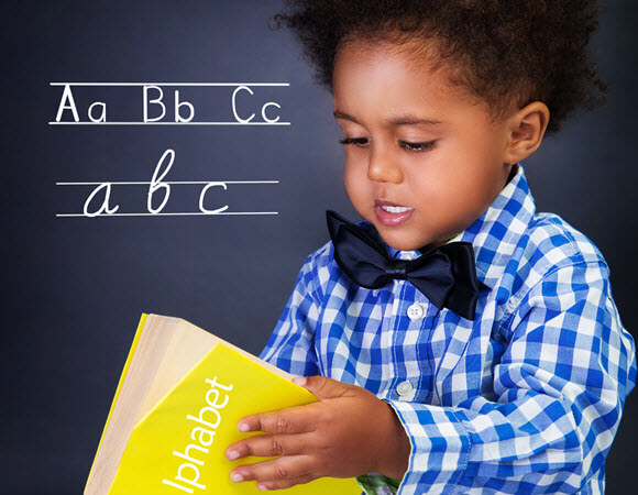 A boy in the 1st grade reading his alphabet book