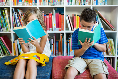 A young boy and girl reading out aloud together
