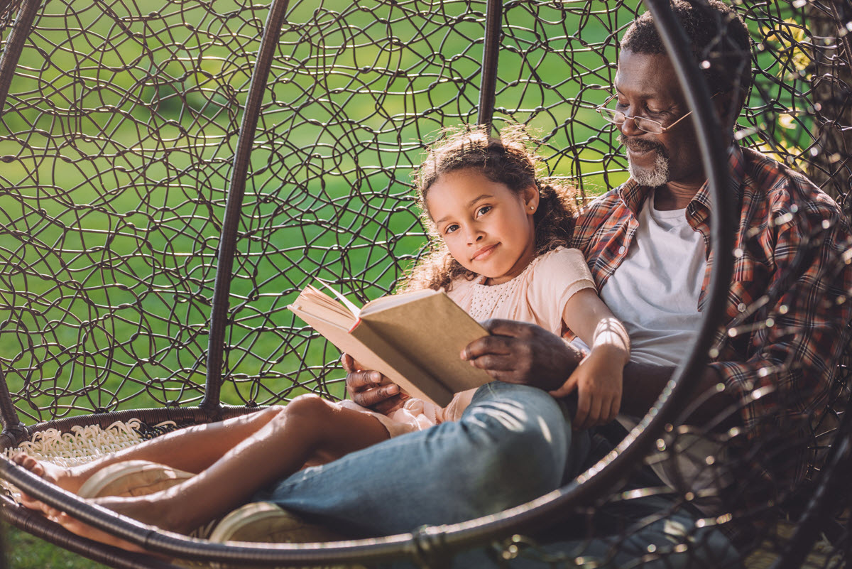 What are read alouds featured image of a young girl being read to outside by her grandpa