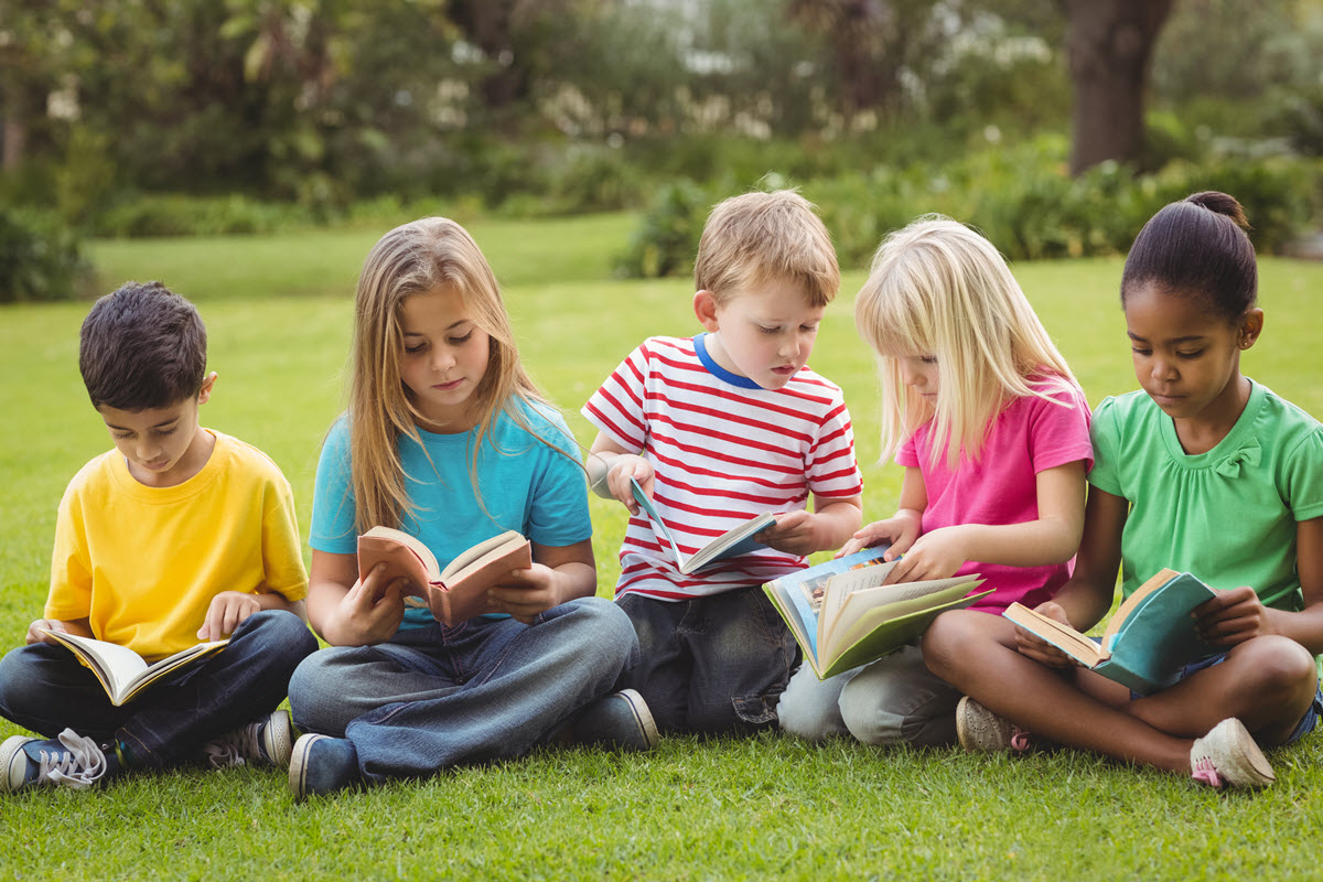 Teaching abc's to preschoolers featured image of 5 preschool kids sitting on the grass while reading their books